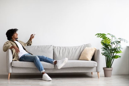 Man sitting on couch adjusting temperature on window unit