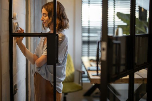 Woman Adjusting Central Air Thermostat 